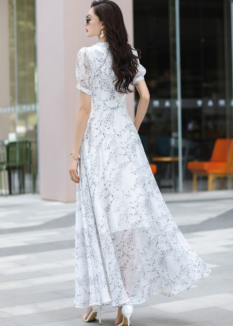 Detail view of a Vivian Seven floral chiffon maxi dress, showcasing the intricate blue and grey botanical print, delicate light blue buttons, and high-waisted design with a fitted belt detail.