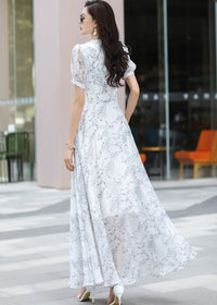 Detail view of a Vivian Seven floral chiffon maxi dress, showcasing the intricate blue and grey botanical print, delicate light blue buttons, and high-waisted design with a fitted belt detail.