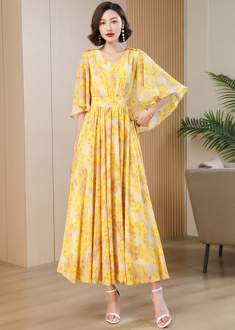 Full-length shot of a yellow and white floral A-line maxi dress with flared sleeves.
