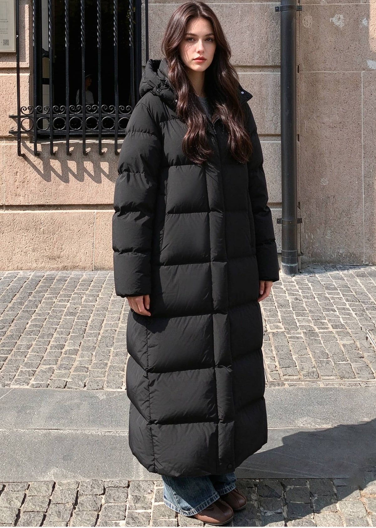 Full length front view of woman wearing black 50 inches length hooded duck down puffer coat