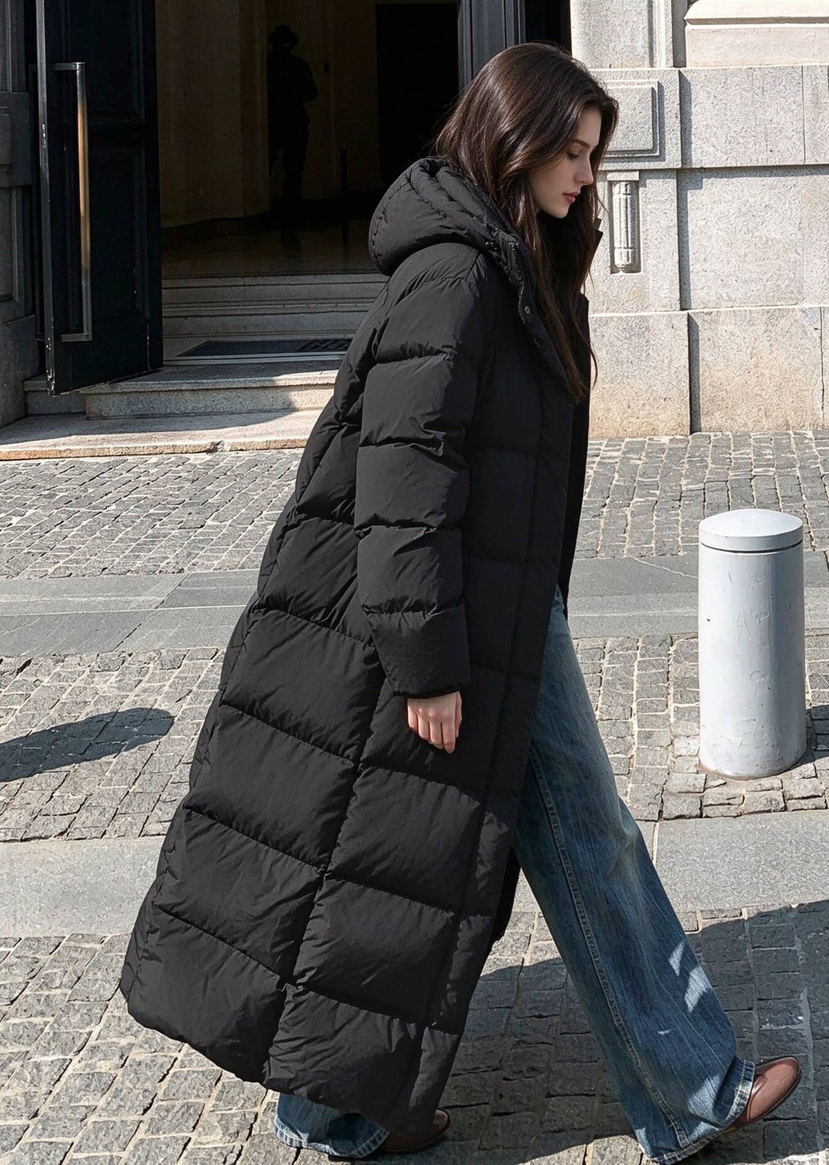 Side view of woman walking outdoors wearing unzipped black 50 inches long duck down puffer coat