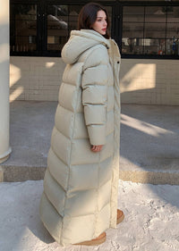 Back side profile view of woman wearing beige 50 inches length hooded duck down puffer coat