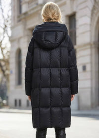 Back view of woman wearing long black box-quilted down puffer coat with hood