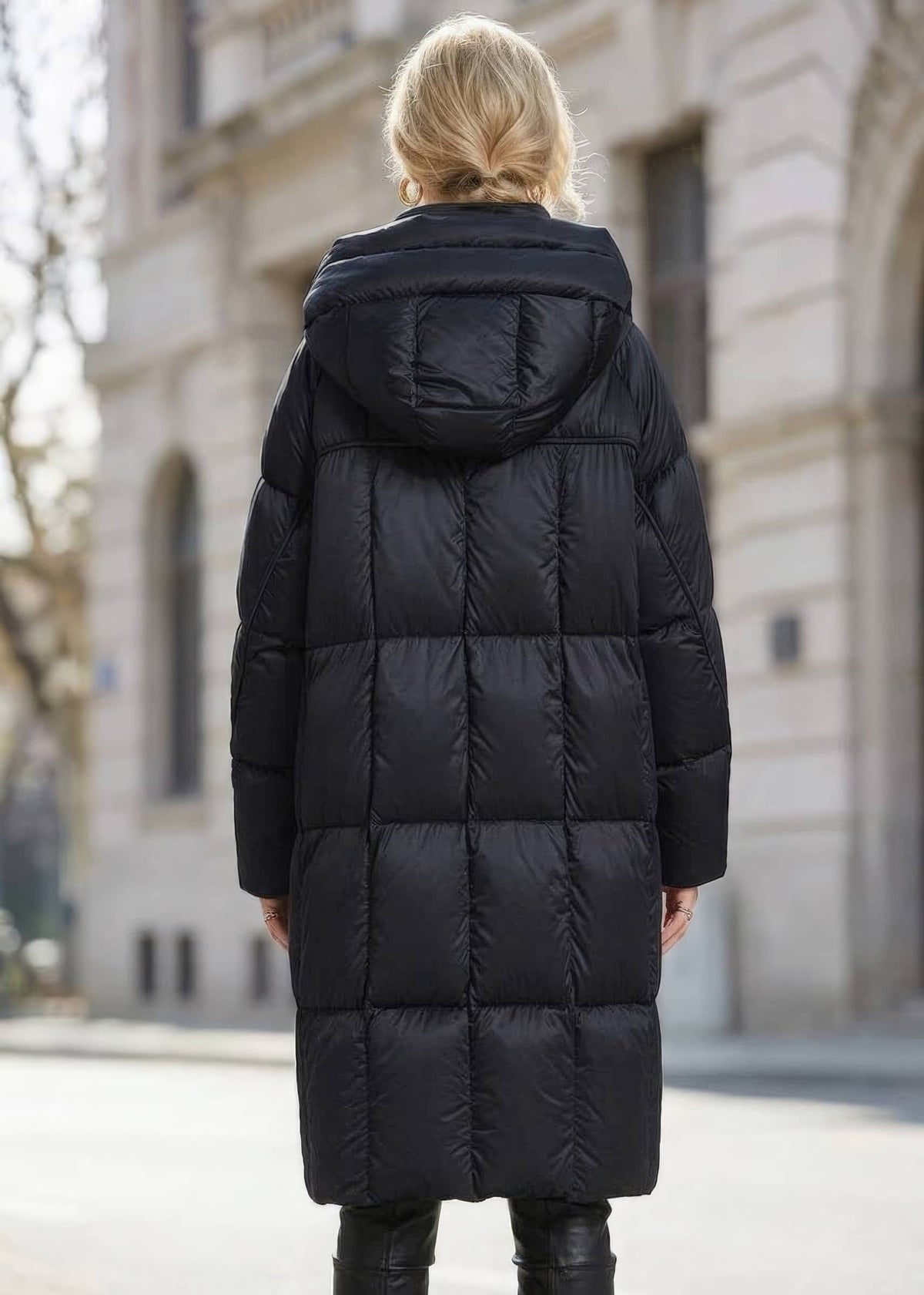 Back view of woman wearing long black box-quilted down puffer coat with hood