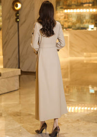 Back view of a floor-length beige trench coat for women featuring a cinched waist and elegant drape.
