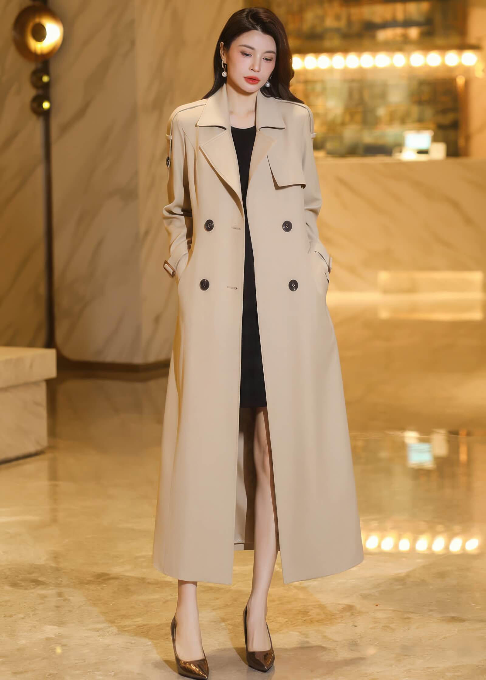 Full-length view of an unbelted beige trench coat worn over a black dress for a chic, layered look.