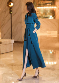 Side profile of a long teal trench coat showing the high slit movement and professional tailoring.