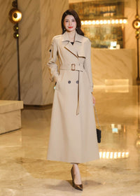 Full-length shot of a classic khaki double-breasted trench coat with a matching waist belt and wide lapels.