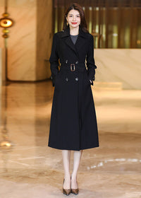Professional studio shot of a classic Vivian Seven black long trench coat with hands in pockets.