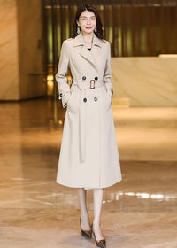 Elegant Vivian Seven beige long trench coat with double-breasted buttons and an adjustable waist belt.