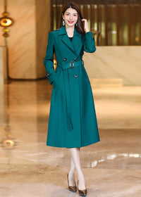 Vibrant Vivian Seven dark teal (peacock green) long trench coat styled with a waist belt and metallic heels.