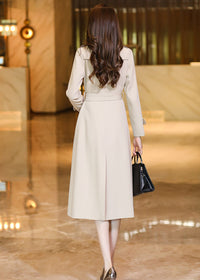 Rear view of the Vivian Seven beige trench coat highlighting the clean lines, belt detail, and professional midi length.
