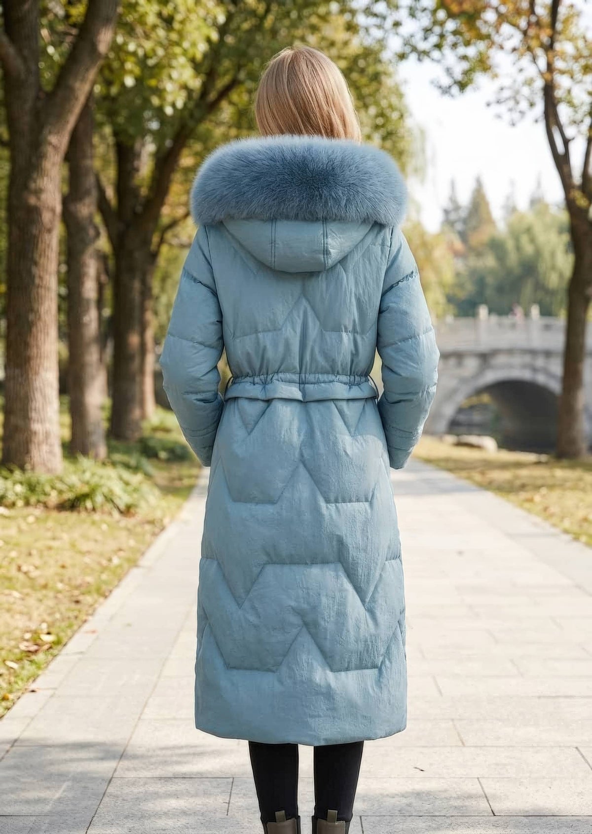 Full length back view of woman wearing dusty blue genuine sheepskin leather down coat with plush fox fur trimmed hood