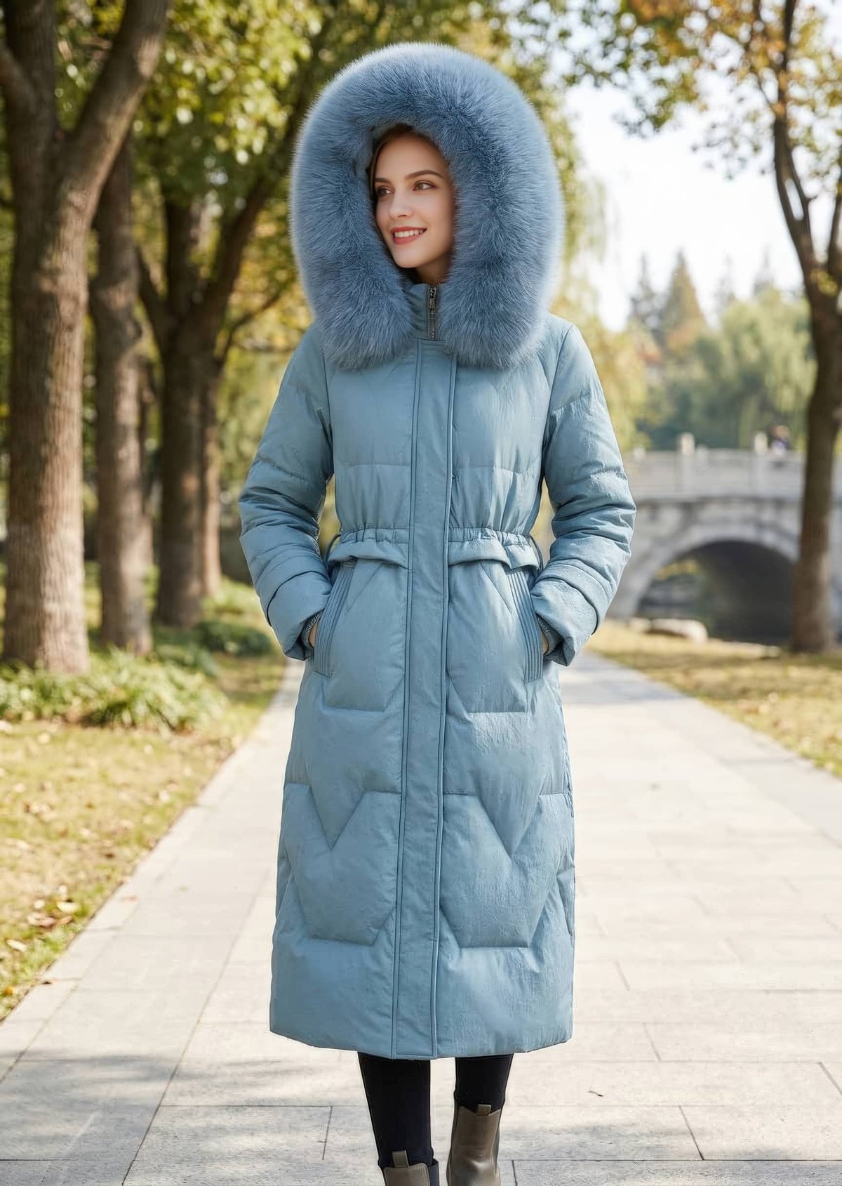Full length front view of smiling woman wearing dusty blue genuine sheepskin leather down coat with hood up and hands in pockets