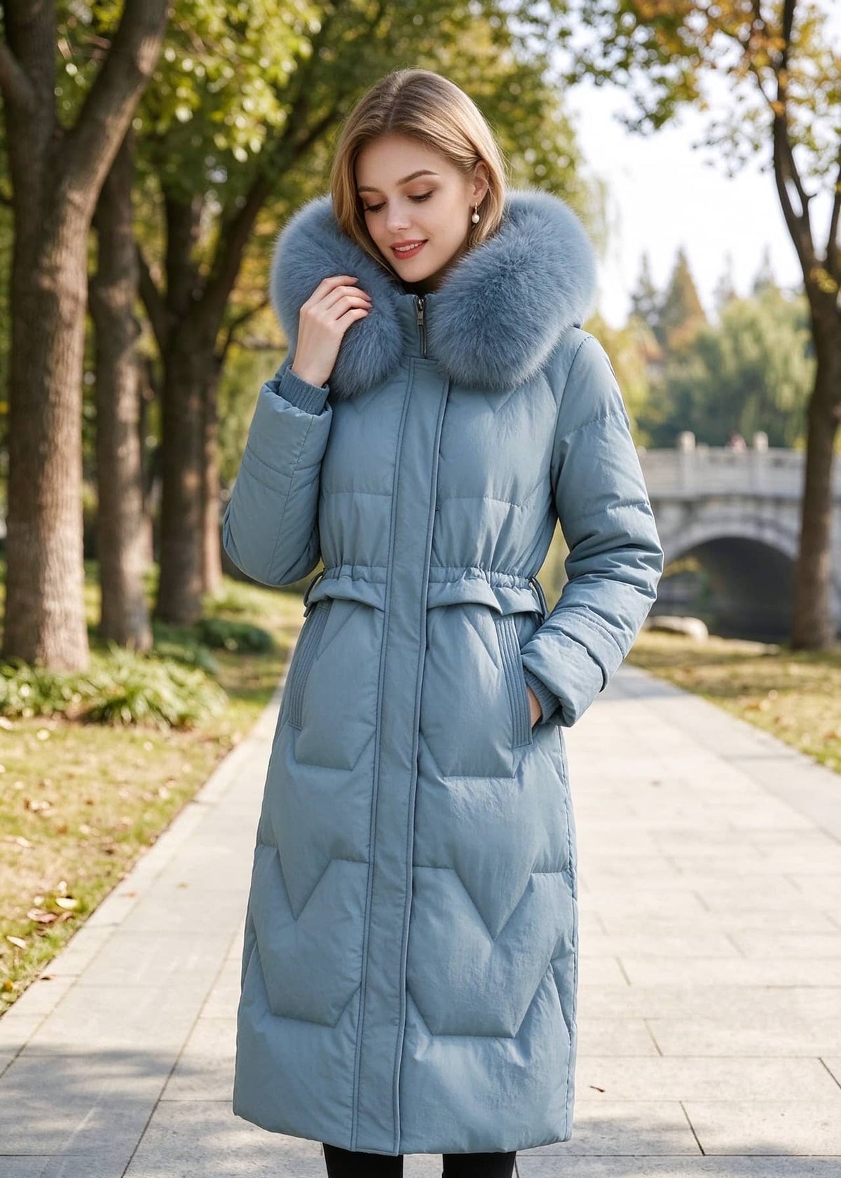 Three-quarter front view of woman wearing dusty blue genuine leather down parka coat with fox fur hood