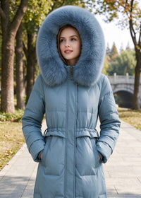Front view portrait of woman with hood up wearing dusty blue genuine sheepskin leather down coat with real fox fur trim