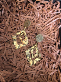 Pair of gold-toned geometric earrings displayed on a bed of brown shredded kraft paper packaging.