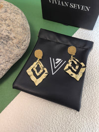 Gold hammered earrings resting on a black faux-leather jewelry pouch branded with a white "V7" logo.