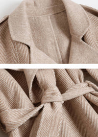 Close-up detail of beige herringbone double face wool cashmere coat lapel collar and tied fabric waist belt