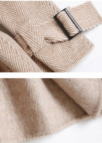 Close-up view of cuff buckle strap detail and soft fabric texture on beige herringbone wool coat