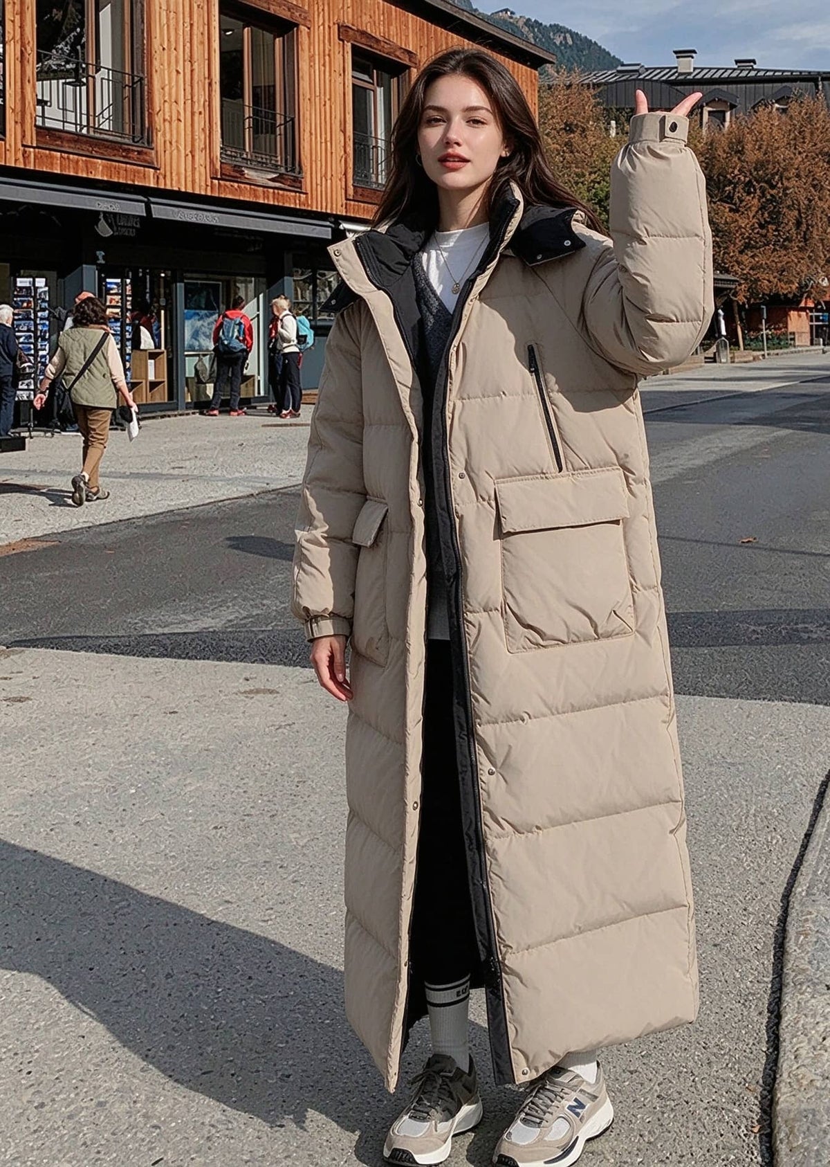 Full length front portrait of woman raising hand wearing beige hooded longline polyfill puffer parka