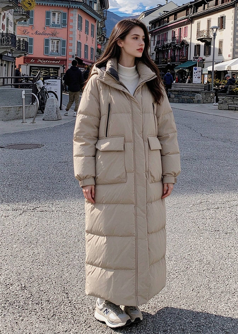 Full length front view of woman in beige zipped hooded longline puffer parka with large cargo flap pockets