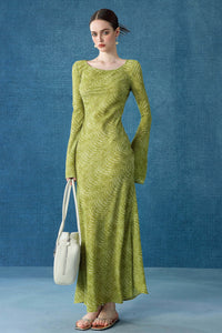 A woman modeling a slim-fit, lime green patterned maxi dress with elegant bell sleeves. She carries a minimalist cream tote bag and wears pearl drop earrings.