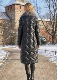 Full length back view of woman wearing black quilted genuine leather long down coat with mink fur shawl collar in snow
