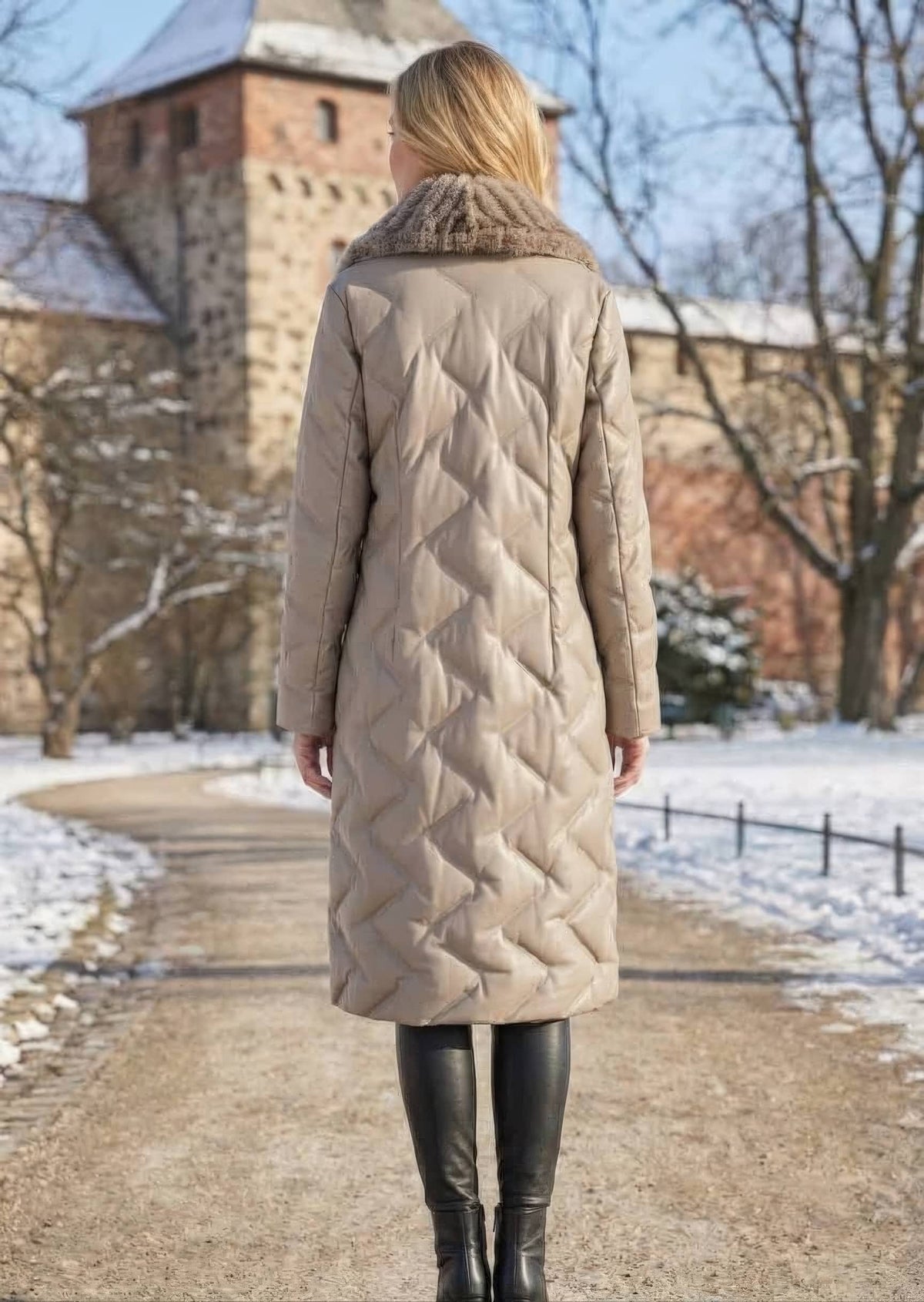 Full length back view of woman wearing taupe quilted genuine sheepskin leather long down coat outdoors in winter