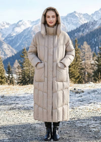 Full length view of woman with hands in pockets wearing beige longline hooded down parka coat against mountain background