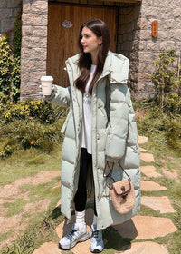 Full length outdoor portrait of woman wearing open sage green high stand collar long down puffer coat