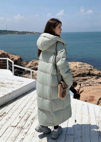 Back side profile view of woman wearing sage green quilted hooded long goose down puffer coat