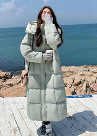 Full length view of woman laughing in gloved hands wearing sage green high collar down puffer coat