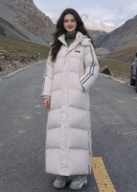Full length front view of smiling woman wearing off-white longline puffer coat with side stripes on scenic mountain road