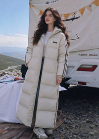 Three-quarter front view of woman wearing unzipped off-white side-stripe longline puffer coat outdoors