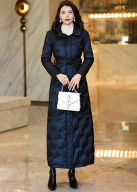 Front view of a model wearing a buttoned midnight navy belted long down coat with a white handbag