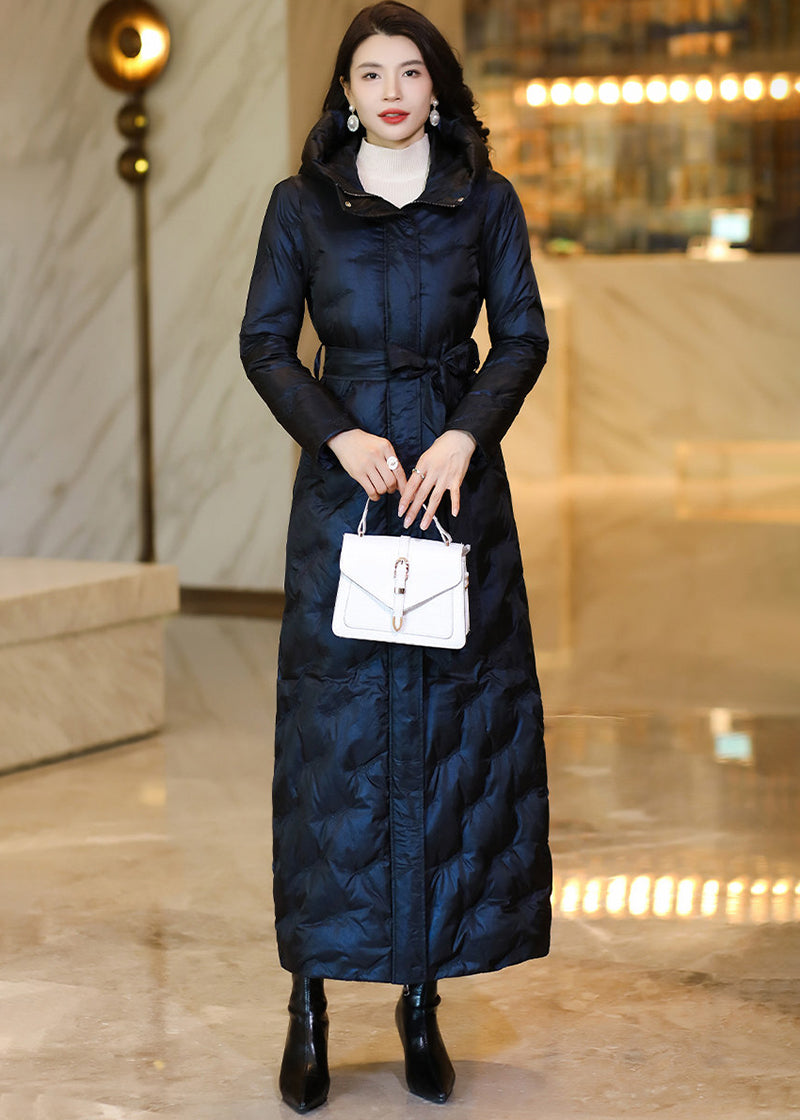 Front view of a model wearing a buttoned midnight navy belted long down coat with a white handbag