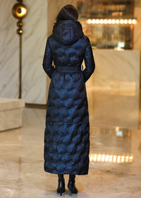 Back view of a model in a hooded midnight navy maxi quilted down parka with a waist-tie belt