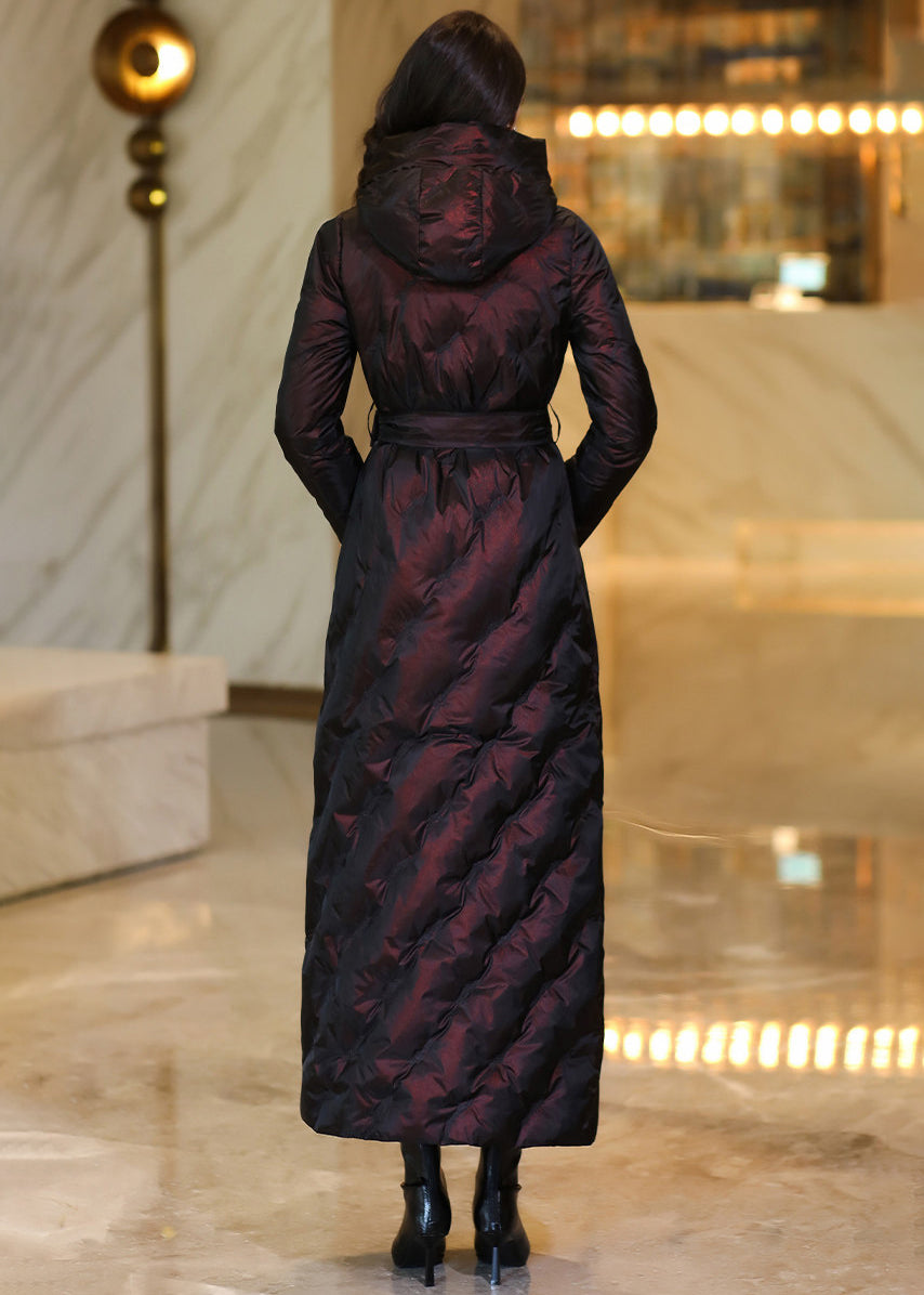 Back view of a model wearing an iridescent deep burgundy full-length hooded down coat with waist belt