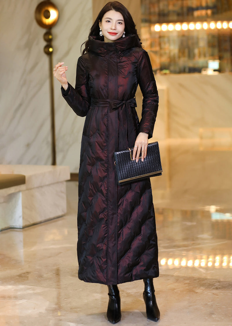 Model carrying a black clutch and wearing a shimmering wine red belted hooded down coat with high stand collar