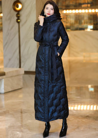 Model wearing a midnight navy shimmer belted maxi down parka with an open coat front