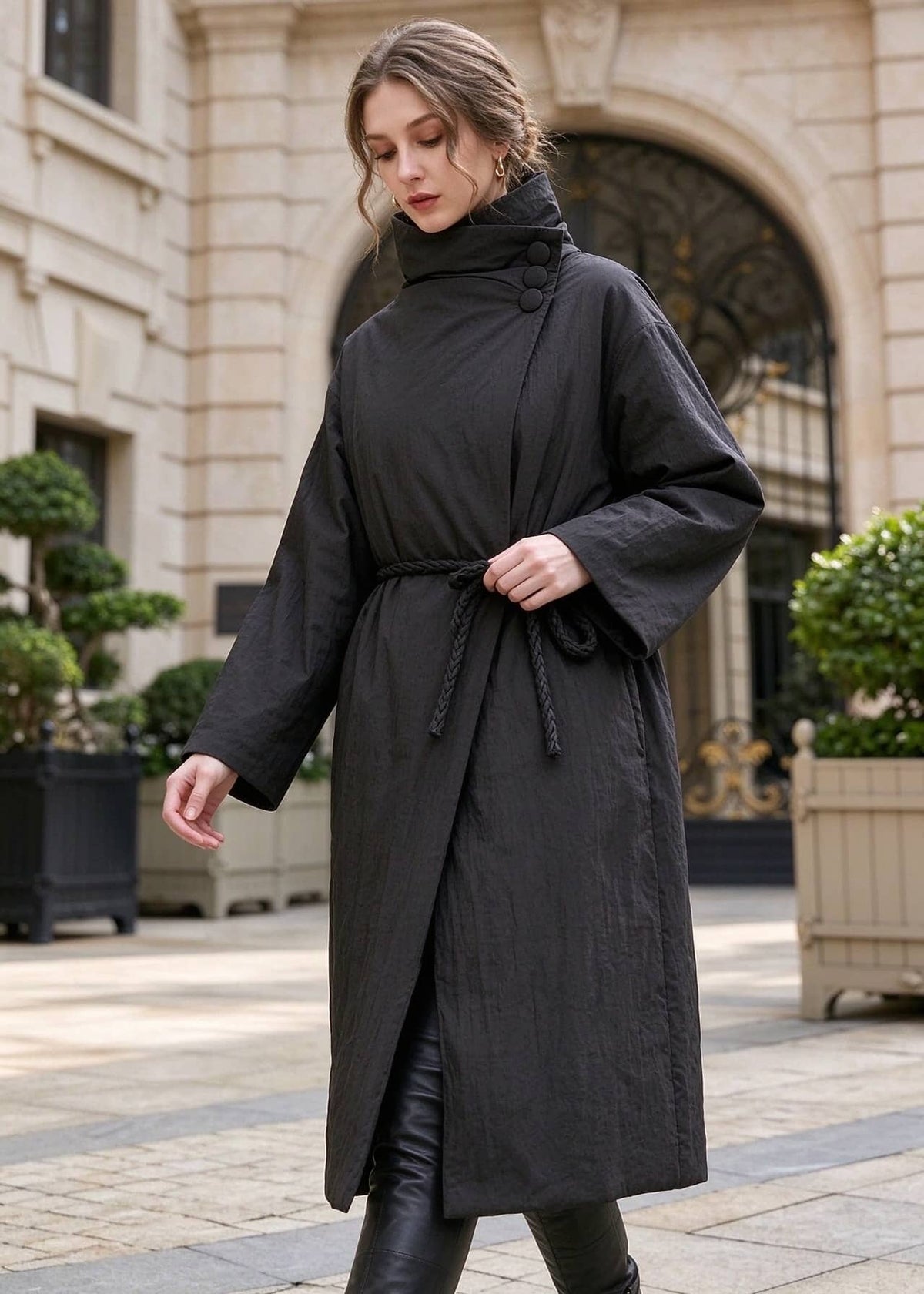 Woman walking in black asymmetric high neck longline down coat with side rope tie