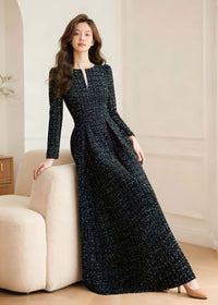 Model leaning against a sofa wearing the Vivian Seven black maxi tweed dress, demonstrating the dress's drape and luxury fabric.