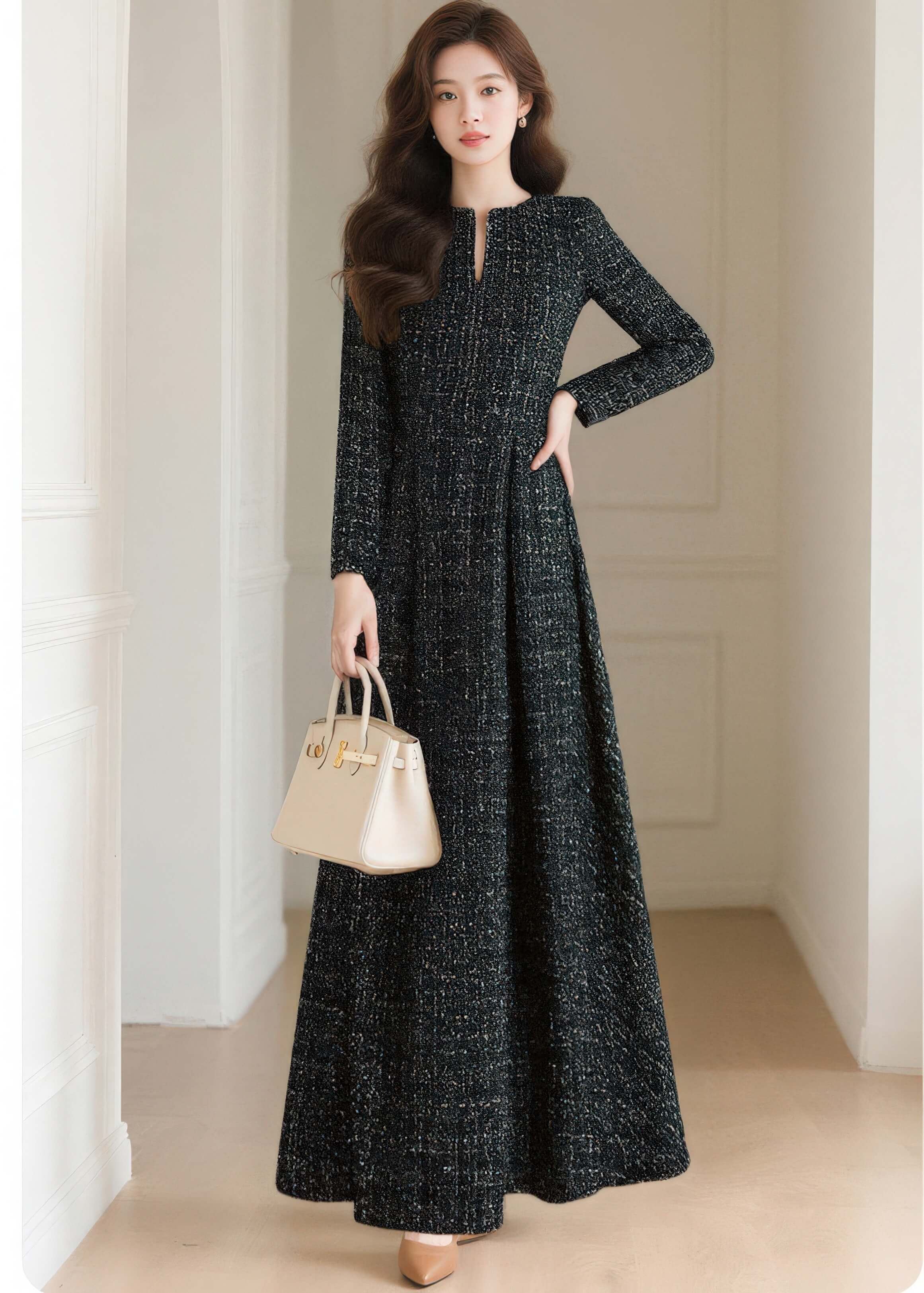 A model posing in the Vivian Seven black tweed maxi dress featuring a sophisticated jewel neckline and long sleeves, holding a cream leather bag.