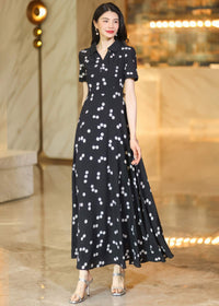 Rear view of a woman wearing a black and white polka dot maxi dress, showing the flowing skirt and long, dark wavy hair.