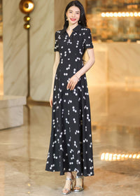 "Portrait of a woman wearing a black lapel collar maxi dress with white polka dots, posing in a well-lit indoor lobby.