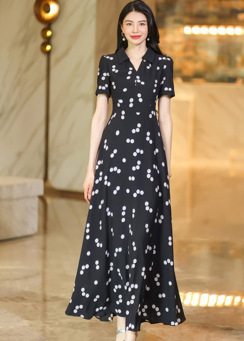 A woman gracefully posing in a flowing polka dot maxi dress, highlighting the elegant drape of the fabric.