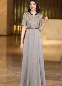 Front view of a woman walking in a champagne A-line maxi dress, showing the flow of the skirt and button-down detail.