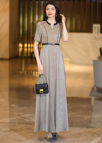 Front view of a woman in a champagne maxi dress holding a small black quilted handbag with a gold chain strap.