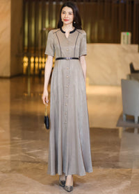 Front view of a woman walking in a champagne A-line maxi dress, showing the flow of the skirt and button-down detail."